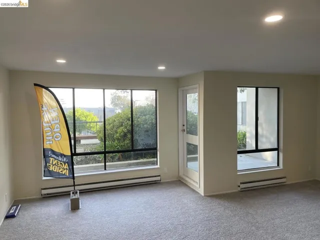 Spacious room featuring multiple large windows, recessed lighting, neutral wall tones, and plush carpeting