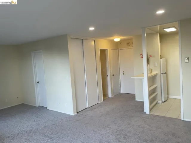 Carpeted living area featuring recessed lighting, a built-in closet with sliding doors, and a breakfast bar with shelving