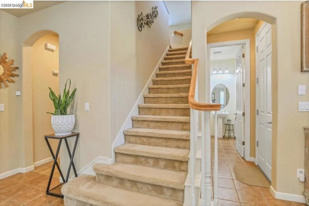 Carpeted staircase with white balusters and a light wood handrail