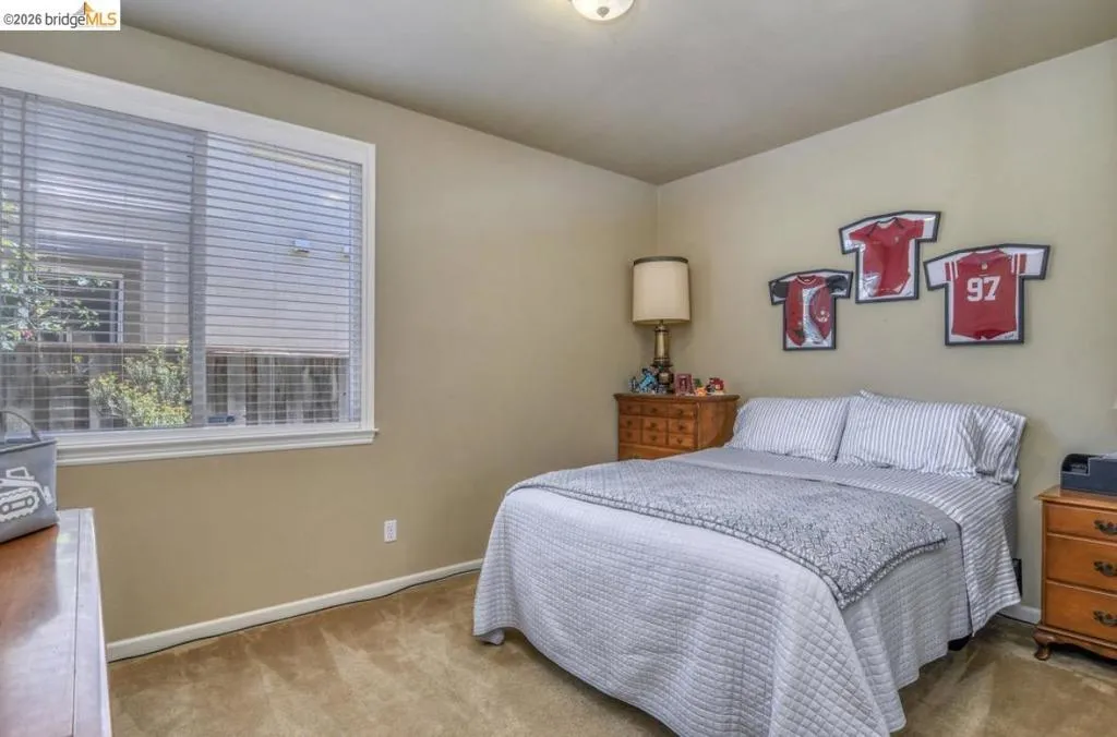 Bedroom featuring a large window with blinds, carpeted flooring, and neutral wall paint