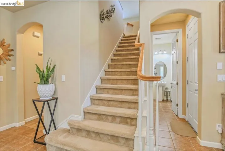 Carpeted staircase with white balusters and a light wood handrail