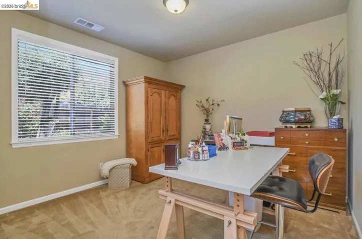 Room featuring neutral-toned walls, patterned carpet flooring, and a single window with horizontal blinds