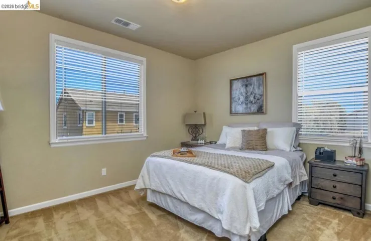 Bedroom featuring two windows with horizontal blinds, neutral wall paint, and carpeted flooring