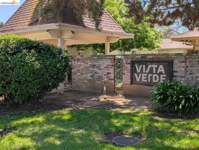 Brick entry monument featuring the "Vista Verde" sign, decorative wrought iron gate, and a covered structure with a shingled roof