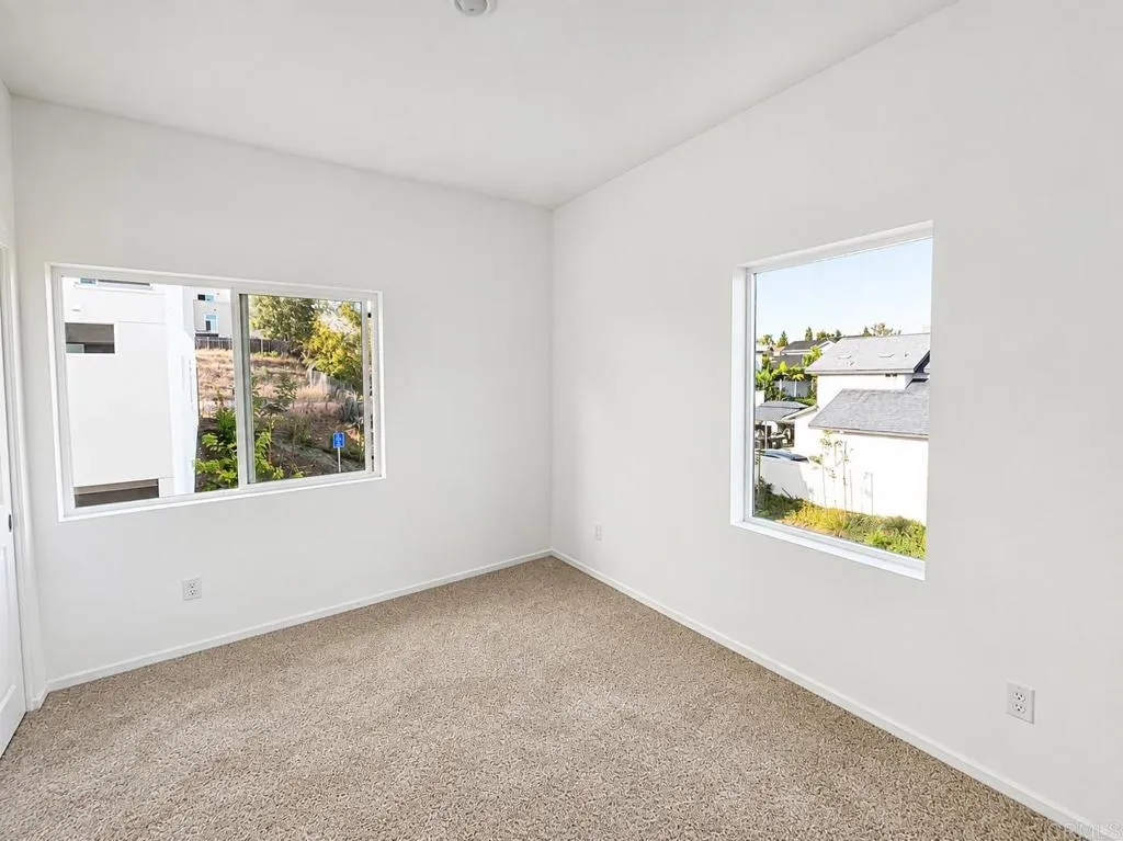 Spacious secondary bedroom with large windows and ample closet space.
