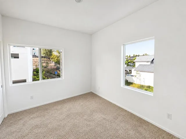 Spacious secondary bedroom with large windows and ample closet space.