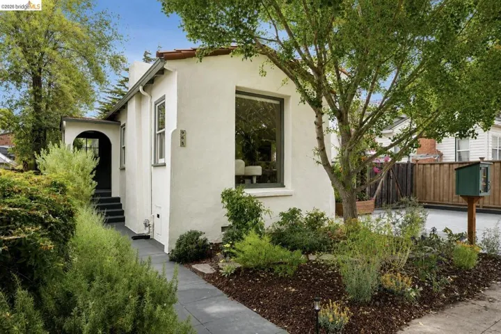 Stucco exterior featuring an arched entryway, dark trim windows, and a tiled roof detail