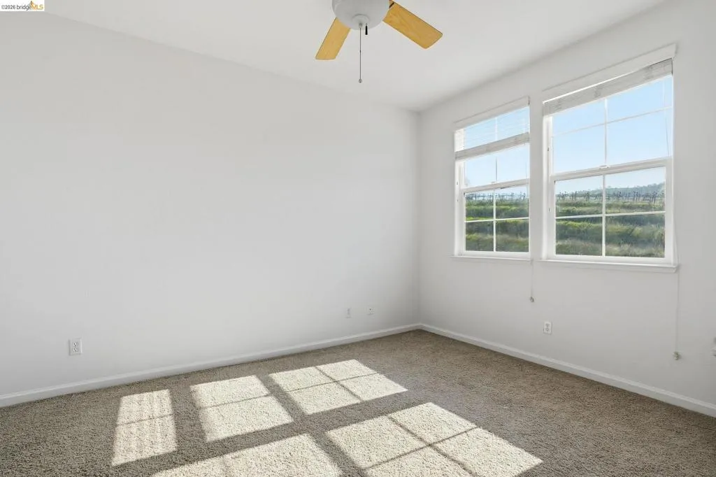Carpeted empty room featuring baseboards and a ceiling fan