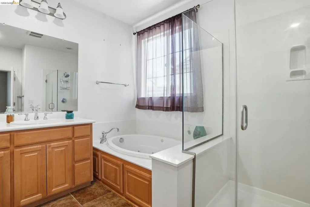 Bathroom featuring a shower stall, vanity, and a whirlpool tub