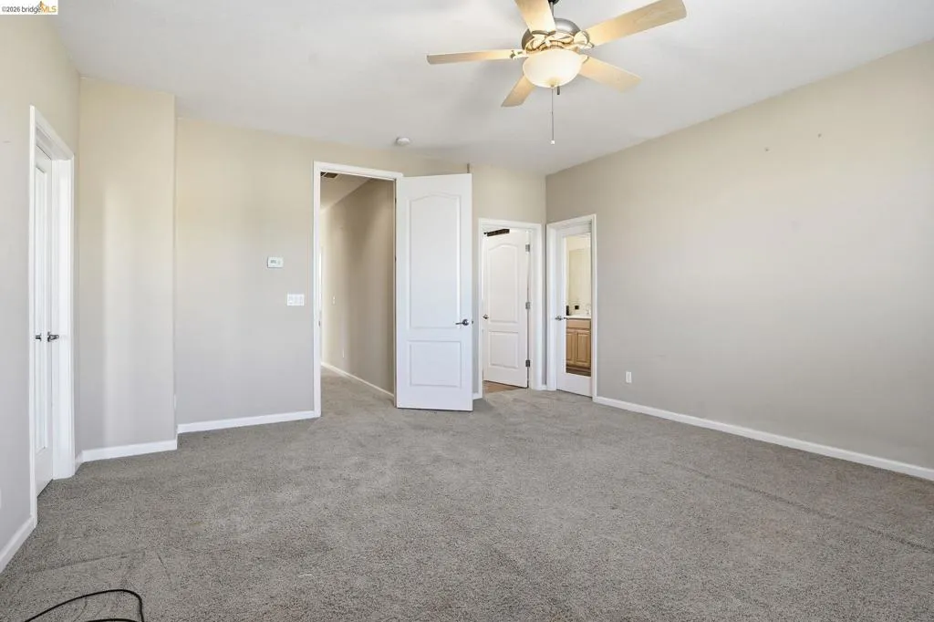 Unfurnished bedroom featuring connected bathroom, carpet, and a ceiling fan