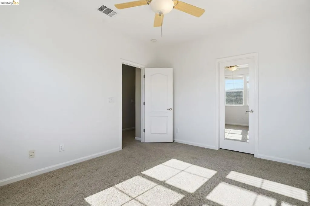 Unfurnished bedroom with light carpet and a ceiling fan