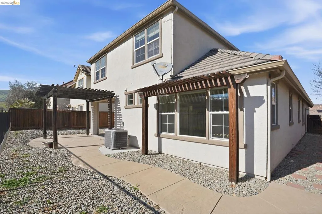 Back of property featuring a fenced backyard, a pergola, stucco siding, and a patio area