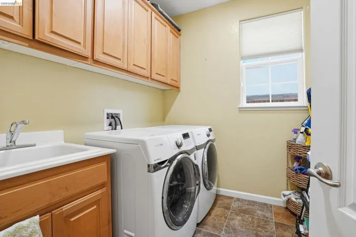 Laundry area featuring washer and dryer, cabinet space, and a textured wall