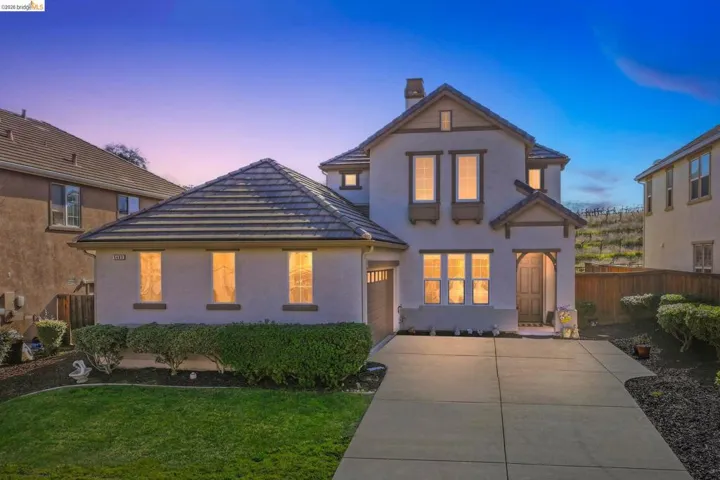 Traditional-style house featuring concrete driveway, a chimney, stucco siding, a tile roof, and an attached garage