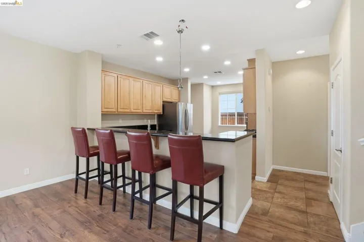 Kitchen featuring a peninsula, dark countertops, a breakfast bar, freestanding refrigerator, and recessed lighting