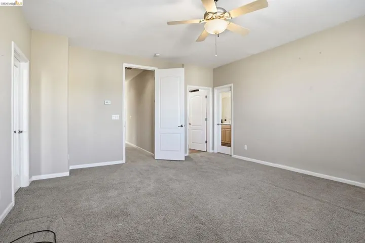 Unfurnished bedroom featuring connected bathroom, carpet, and a ceiling fan