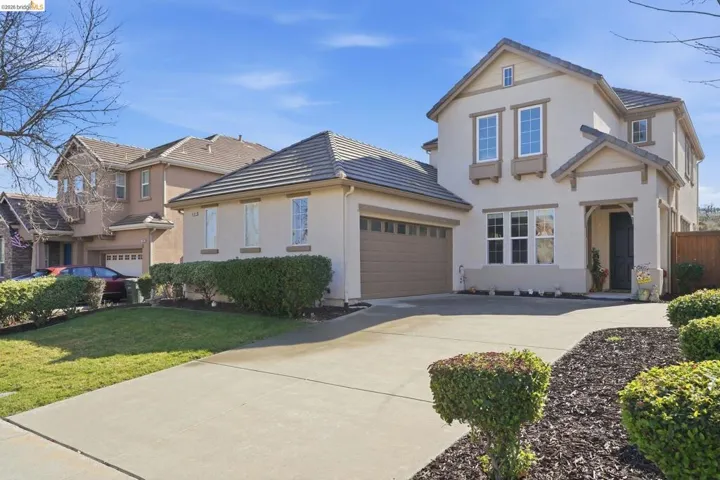 Traditional-style home featuring driveway, stucco siding, a tiled roof, an attached garage, and a front yard
