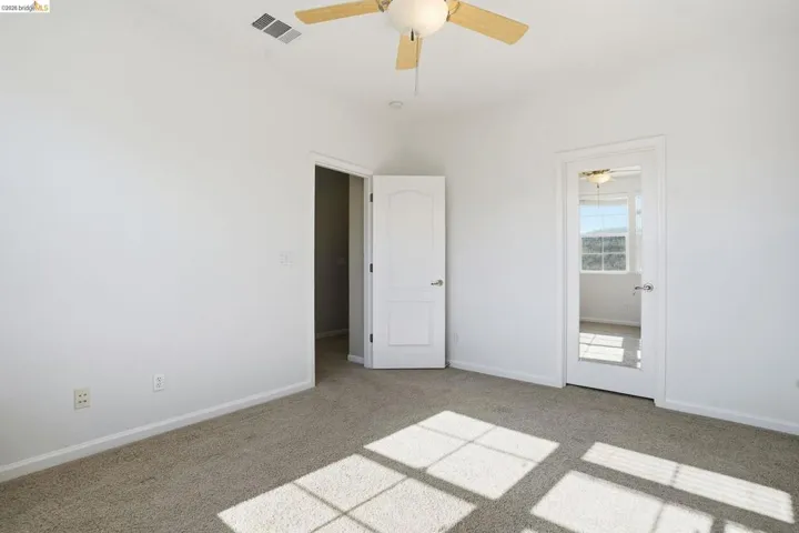 Unfurnished bedroom with light carpet and a ceiling fan