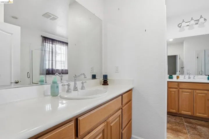 Bathroom featuring a shower stall, two vanities, and a textured wall