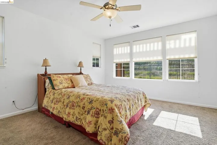 Bedroom with light carpet and a ceiling fan