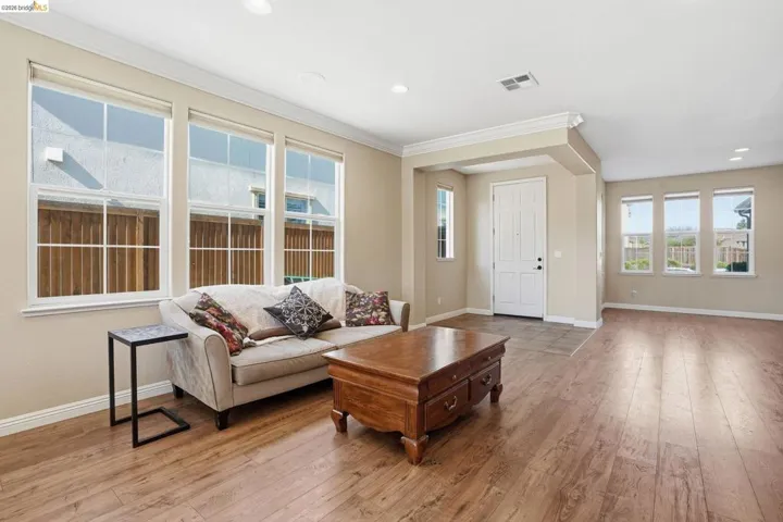 Living room featuring light wood-type flooring, recessed lighting, and ornamental molding