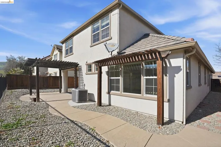Back of property featuring a fenced backyard, a pergola, stucco siding, and a patio area
