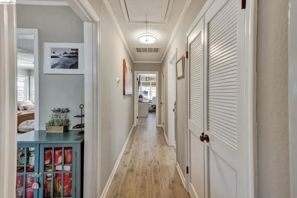 Hallway featuring wood-finish flooring, light grey wall paint, and white trim