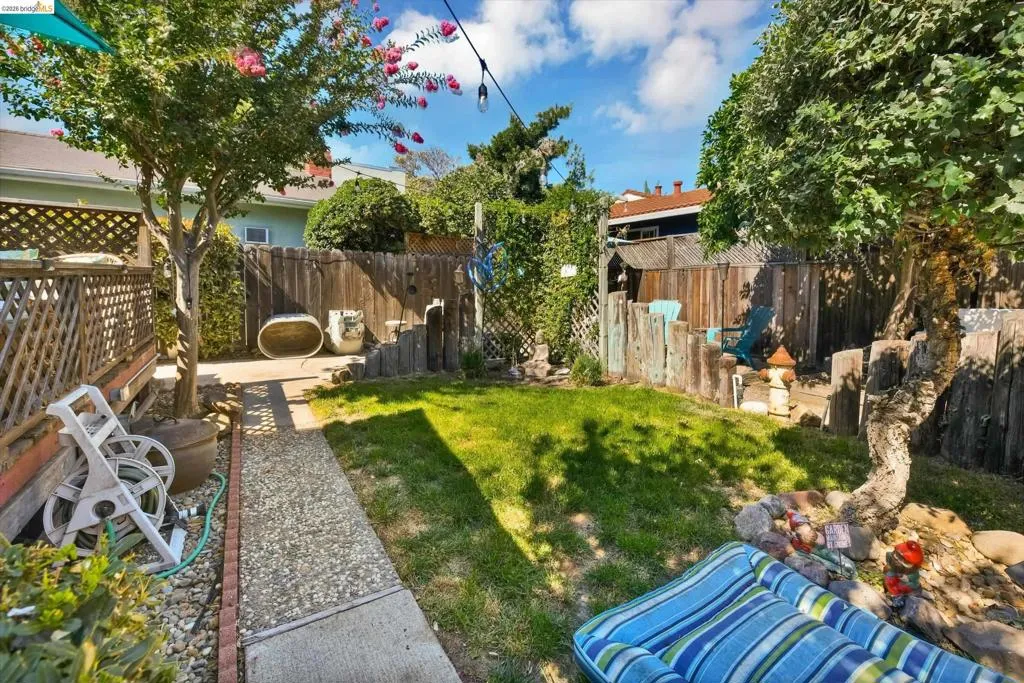 Expansive backyard featuring a central lawn, mature trees, and a concrete pathway