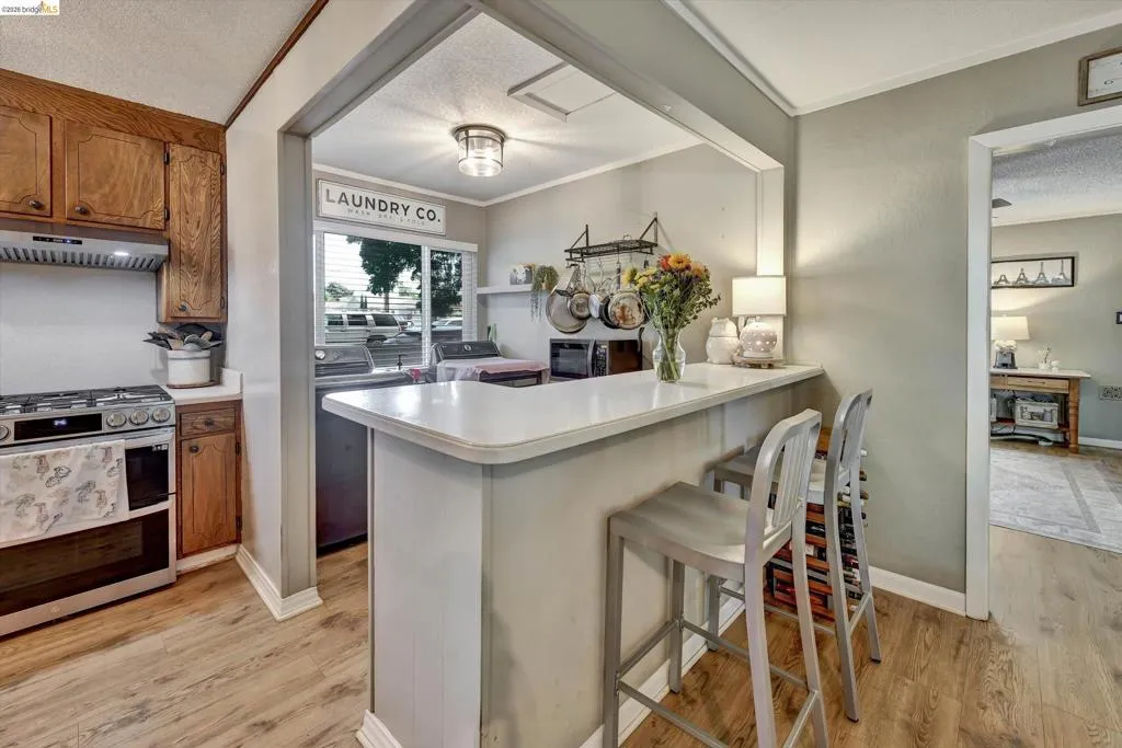 Kitchen featuring a breakfast bar with seating, wood-finish flooring, and a gas range with an overhead exhaust hood