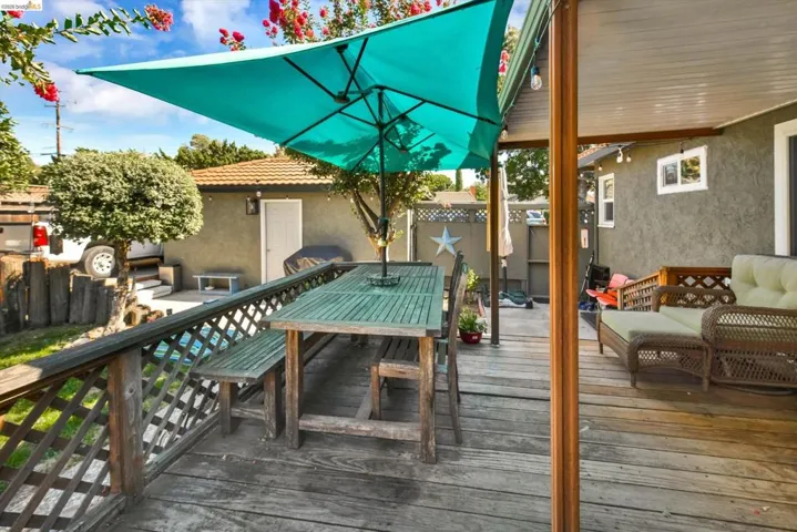 Expansive wood-finish deck featuring a lattice railing, overhead lighting, and an attached covered patio