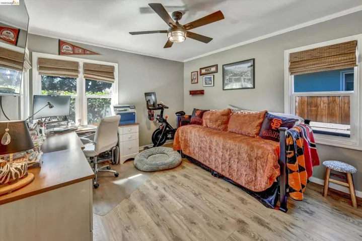 Room featuring wood-finish flooring, multiple windows with natural fiber shades, a ceiling fan with integrated lighting, and light-toned wall paint