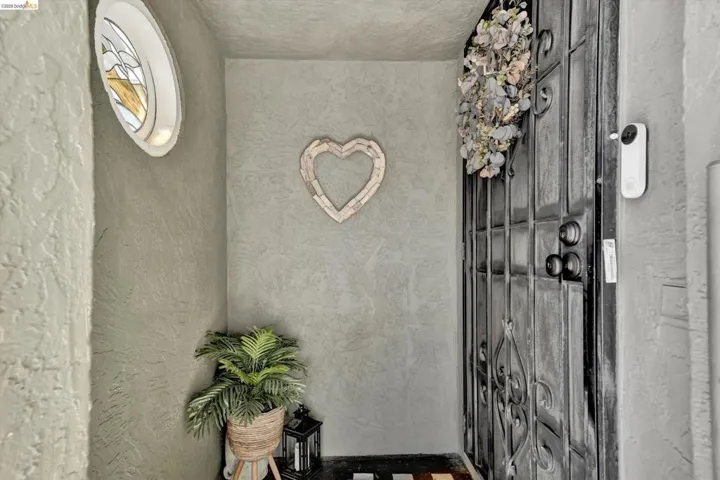 Entryway featuring a wrought iron security door, textured stucco walls, and an oval stained glass window