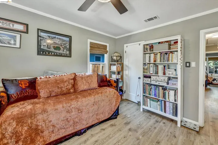 Interior room featuring wood-finish flooring, a ceiling fan, and white crown molding