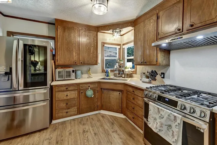 Kitchen featuring wood-finish cabinetry, light-toned countertops, and wood-finish flooring