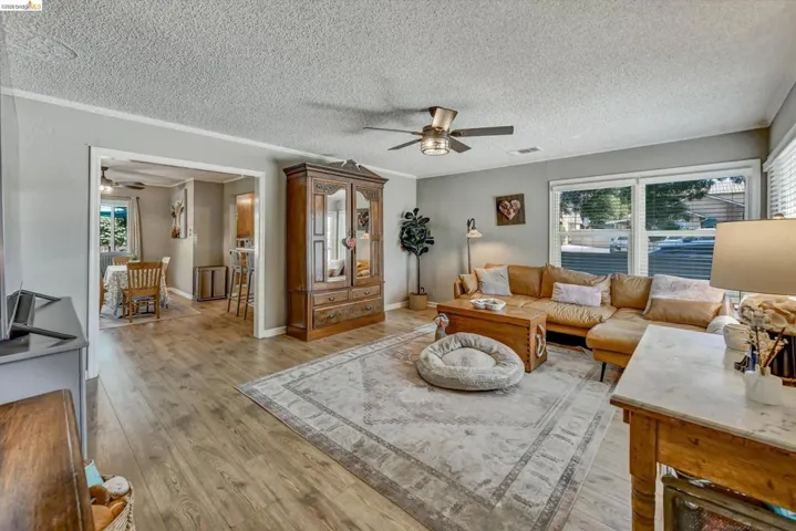 Living area with wood-finish flooring, light gray wall paint, and a ceiling fan with integrated lighting