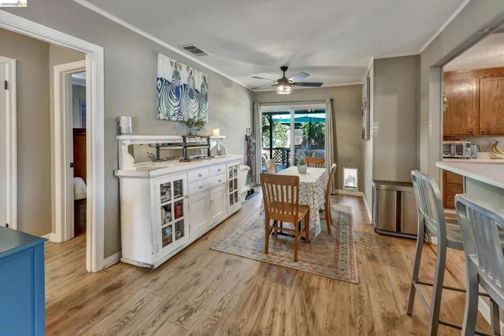 Open-concept dining area featuring wood-finish flooring, a ceiling fan, and sliding glass doors providing access to an outdoor patio