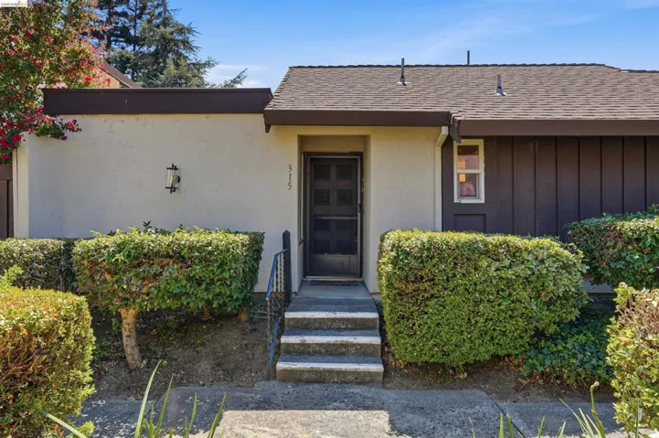 Front exterior featuring stucco and vertical panel siding