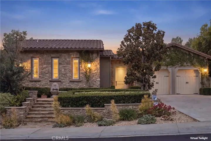 Elegant single-story residence with stone façade, gated courtyard, and three-car garage.