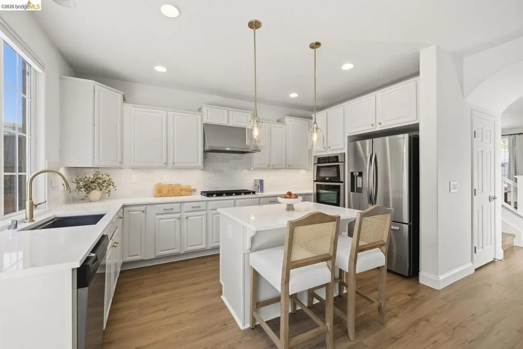 Dining area featuring a modern linear chandelier, multiple windows with natural light, and wood-finish flooring