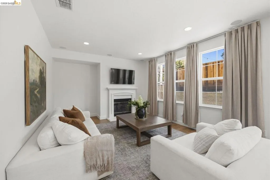 Spacious room featuring wood-finish flooring, multiple windows with white trim, recessed lighting, and a white upholstered headboard