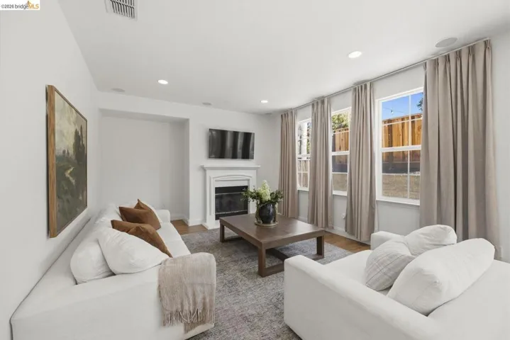 Spacious room featuring wood-finish flooring, multiple windows with white trim, recessed lighting, and a white upholstered headboard