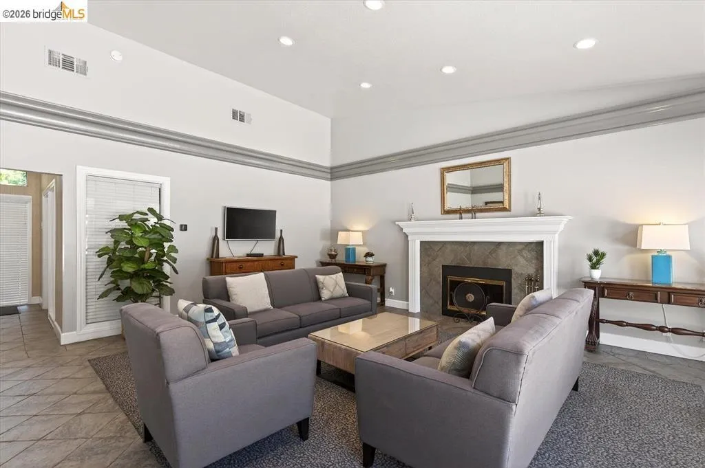 Bright and open living area featuring a fireplace with stone surround and dark insert, recessed ceiling lighting, and neutral wall finishes