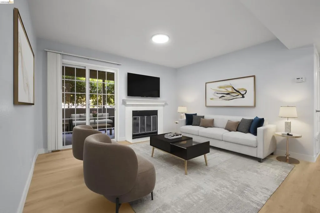 Bright, open living space featuring hardwood flooring, a neutral upholstered sectional sofa, and a black coffee table