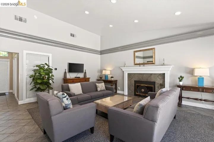 Bright and open living area featuring a fireplace with stone surround and dark insert, recessed ceiling lighting, and neutral wall finishes