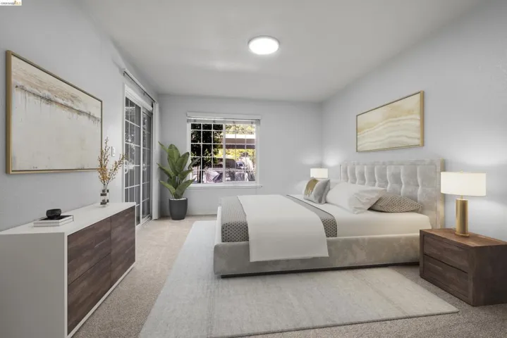 Spacious primary bedroom featuring a tufted upholstered bed frame, wood-finish nightstands with integrated lighting, neutral carpeting, and recessed ceiling lights