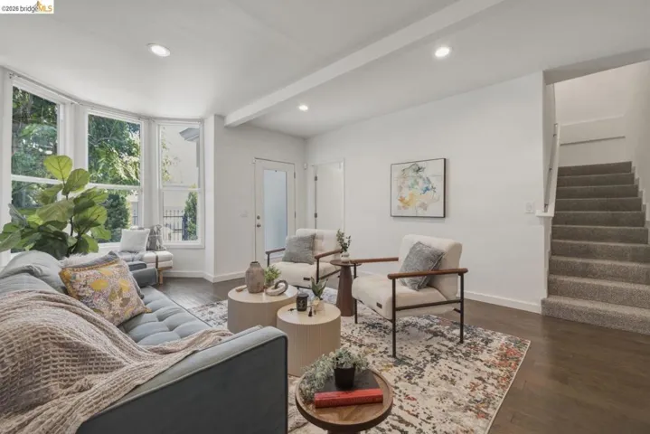 Living room featuring a bay window, recessed lighting, wood-finish flooring, and a carpeted staircase