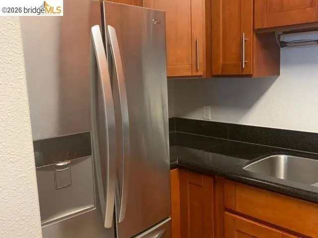 Stainless steel refrigerator with a built-in ice and water dispenser, complemented by wood cabinetry