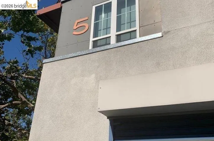 Stucco exterior with a modern window, architectural paneling, and an awning