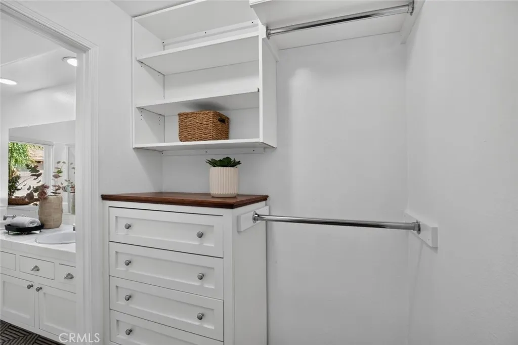 Primary closet with built in dresser and shelving for maximized storage
