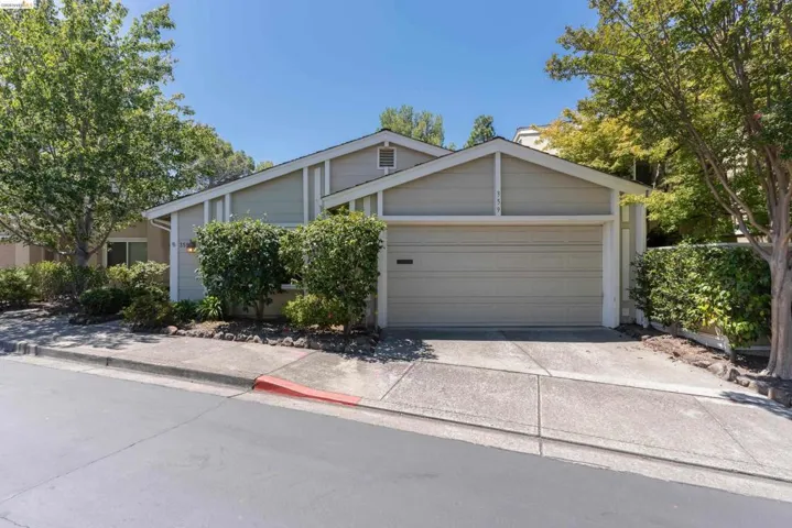 Exterior featuring a two-car garage, neutral-toned siding, a concrete driveway, and mature landscaping